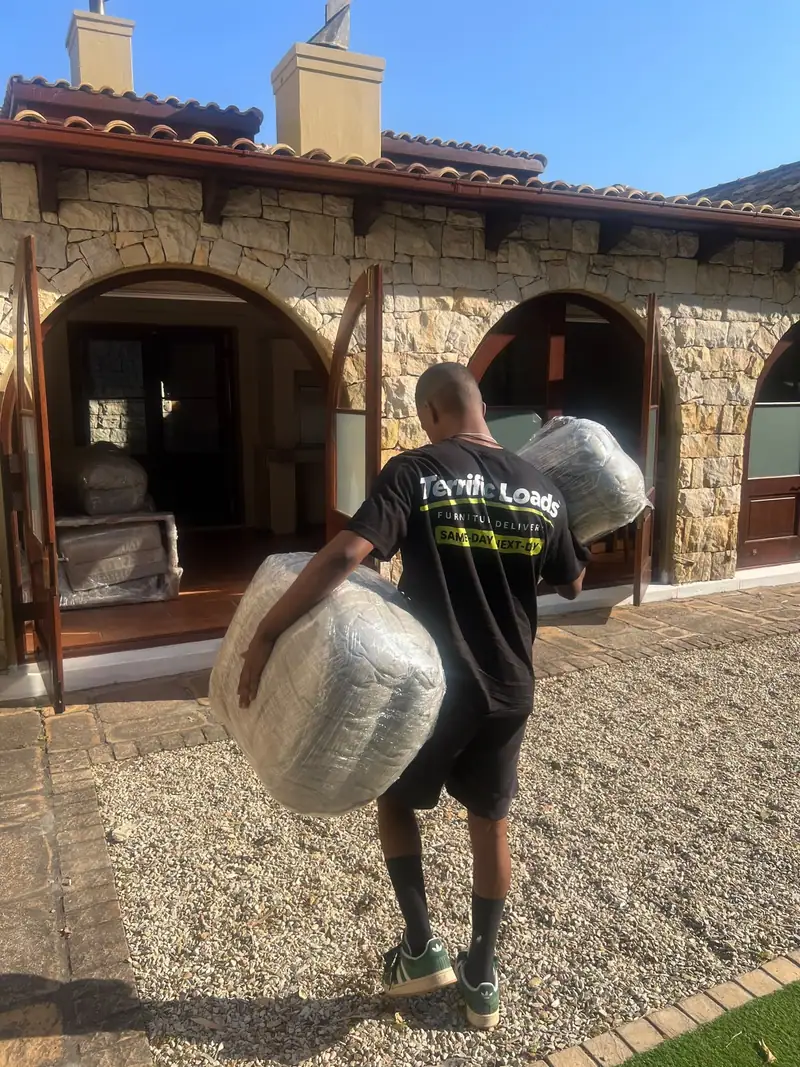 Team member carrying wrapped items to a customer's front door
